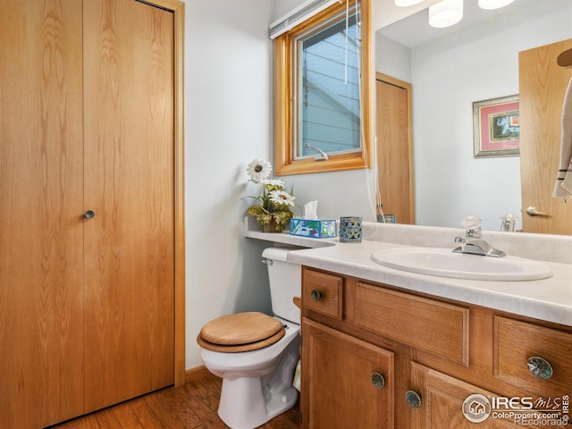 bathroom with toilet, hardwood / wood-style flooring, and vanity