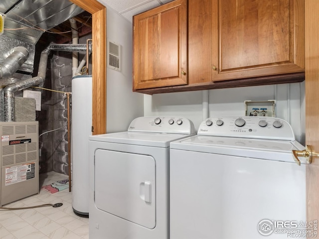 clothes washing area with heating unit, water heater, washer and dryer, and cabinets