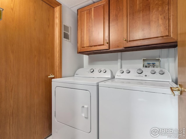 washroom featuring cabinets and washer and clothes dryer