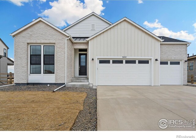 view of front of home with brick siding, board and batten siding, concrete driveway, and an attached garage