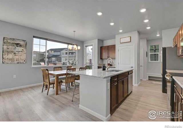 kitchen featuring a notable chandelier, light hardwood / wood-style floors, a kitchen island with sink, appliances with stainless steel finishes, and sink