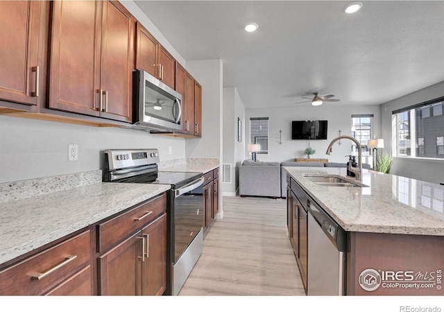 kitchen featuring sink, ceiling fan, an island with sink, light stone countertops, and appliances with stainless steel finishes