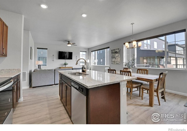 kitchen with pendant lighting, an island with sink, light hardwood / wood-style floors, appliances with stainless steel finishes, and sink