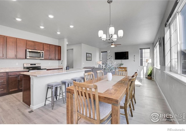 dining area featuring ceiling fan with notable chandelier, sink, and light hardwood / wood-style flooring