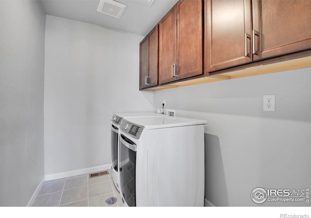 washroom featuring separate washer and dryer, cabinets, and light tile patterned floors