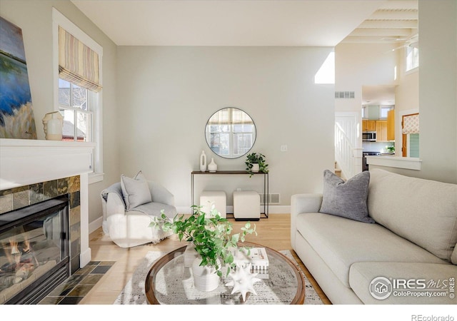 living room with a tile fireplace and hardwood / wood-style floors