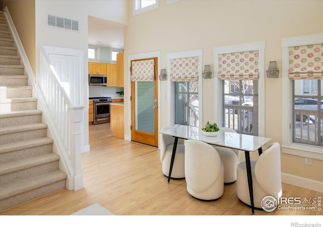 dining area featuring light hardwood / wood-style flooring and a towering ceiling