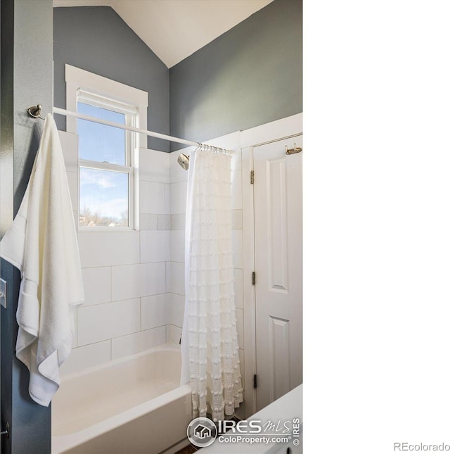 bathroom with shower / bathtub combination with curtain and vaulted ceiling