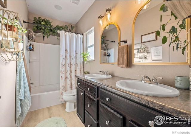 full bathroom featuring toilet, wood-type flooring, vanity, and shower / bathtub combination with curtain