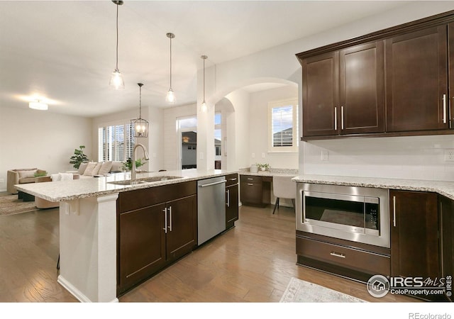 kitchen featuring pendant lighting, hardwood / wood-style floors, appliances with stainless steel finishes, dark brown cabinets, and sink