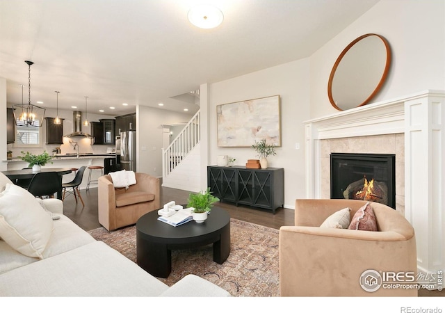 living room featuring sink, a fireplace, an inviting chandelier, and dark wood-type flooring