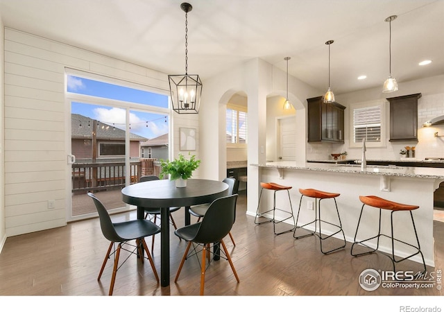 dining area with sink, dark hardwood / wood-style flooring, and a notable chandelier