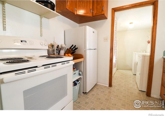 kitchen featuring white appliances and washing machine and clothes dryer