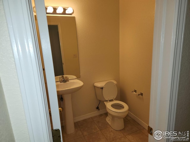 bathroom with toilet, tile patterned flooring, and sink