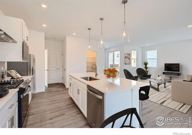 kitchen featuring sink, white cabinets, decorative light fixtures, a kitchen island with sink, and appliances with stainless steel finishes