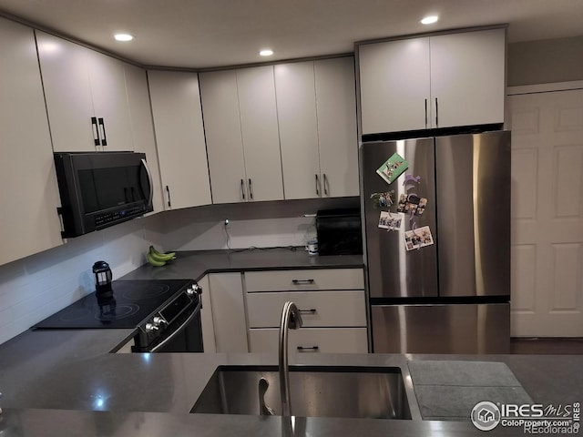 kitchen with sink, electric range oven, white cabinets, and stainless steel refrigerator