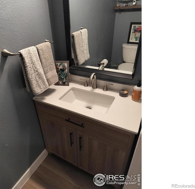 bathroom featuring toilet, hardwood / wood-style flooring, and vanity