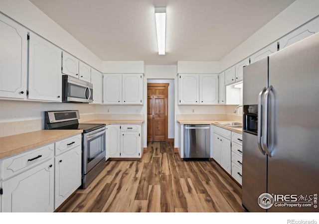 kitchen with dark wood-type flooring, sink, white cabinets, and stainless steel appliances