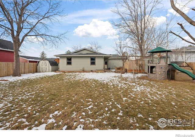 snow covered house featuring a playground and a storage shed