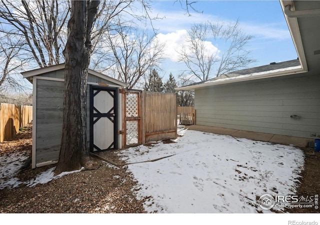 yard layered in snow featuring a storage shed