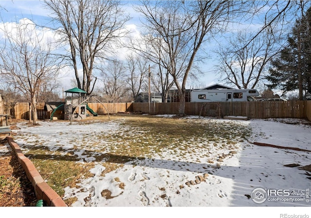 yard layered in snow featuring a playground