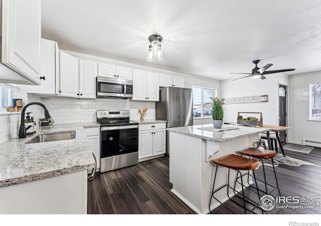 kitchen featuring a center island, stainless steel appliances, tasteful backsplash, white cabinetry, and sink