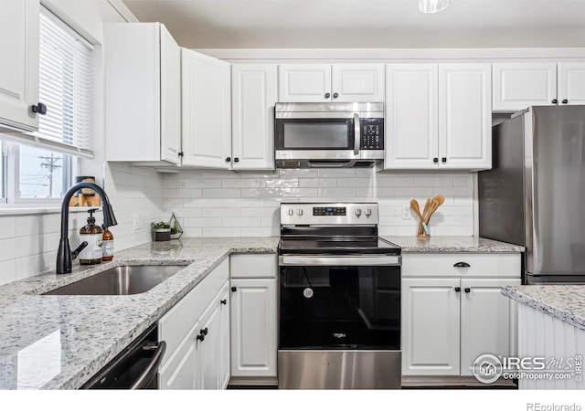 kitchen with stainless steel appliances, white cabinets, decorative backsplash, and sink