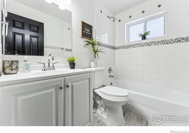 full bathroom featuring tiled shower / bath combo, vanity, and toilet