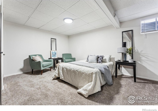 carpeted bedroom featuring beam ceiling and a drop ceiling