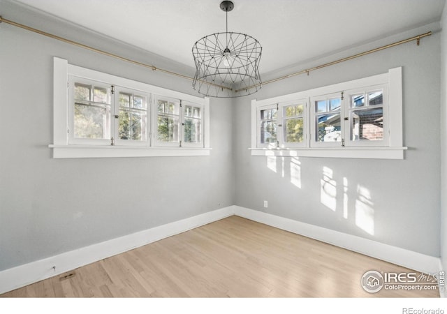 empty room with a notable chandelier and hardwood / wood-style floors