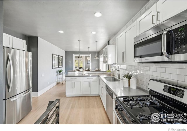 kitchen with kitchen peninsula, appliances with stainless steel finishes, white cabinetry, and sink