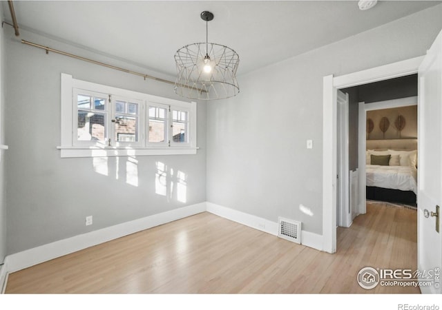 empty room featuring an inviting chandelier and hardwood / wood-style floors