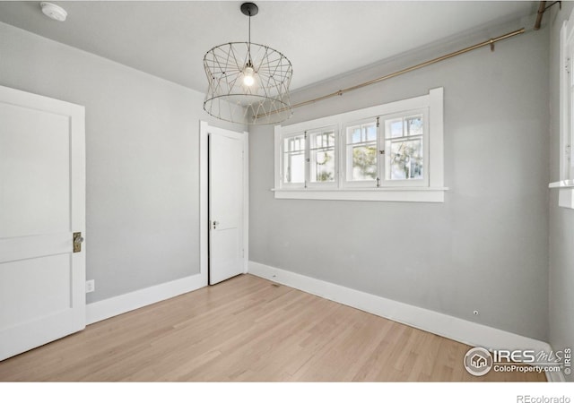 spare room featuring wood-type flooring and a chandelier