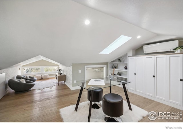 home office featuring light wood-type flooring, built in features, a wall unit AC, and vaulted ceiling with skylight