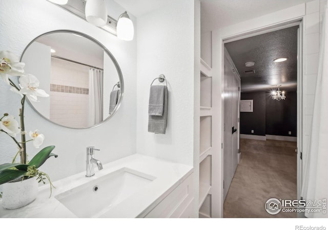 bathroom featuring a shower with shower curtain, vanity, a textured ceiling, an inviting chandelier, and built in shelves