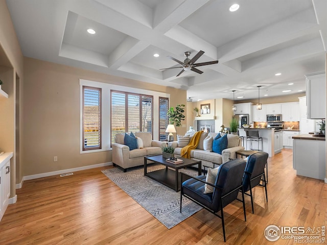 living room featuring light hardwood / wood-style floors, ceiling fan, coffered ceiling, and beam ceiling