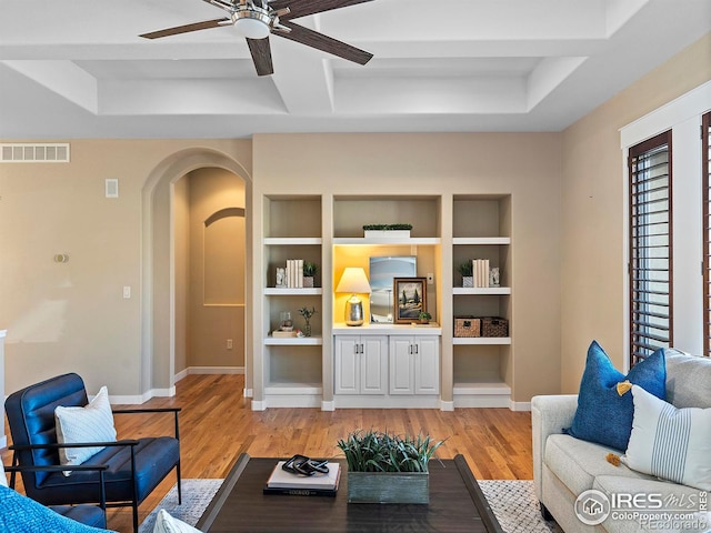 living room with light hardwood / wood-style floors, ceiling fan, coffered ceiling, and built in features