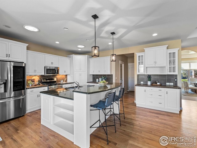 kitchen with an island with sink, appliances with stainless steel finishes, and white cabinetry