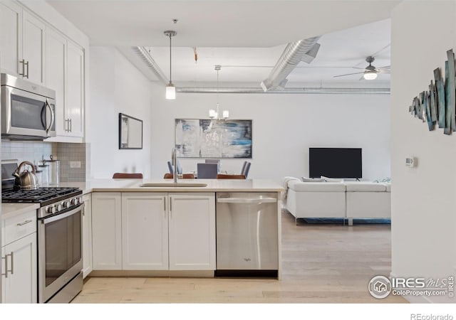 kitchen featuring hanging light fixtures, decorative backsplash, white cabinetry, appliances with stainless steel finishes, and sink