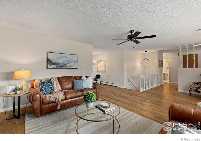 living room with baseboard heating, a textured ceiling, ceiling fan, and light hardwood / wood-style floors