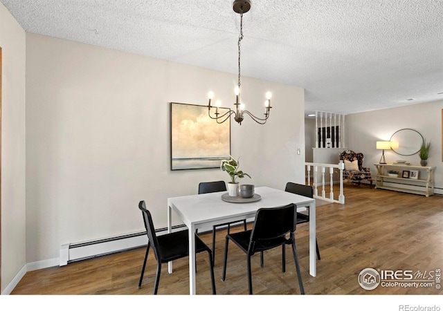 dining space featuring a baseboard heating unit, an inviting chandelier, hardwood / wood-style floors, and a textured ceiling