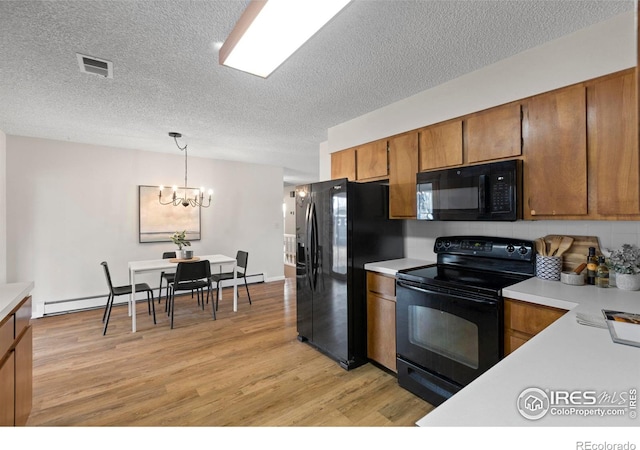 kitchen with a textured ceiling, hanging light fixtures, light hardwood / wood-style floors, black appliances, and an inviting chandelier