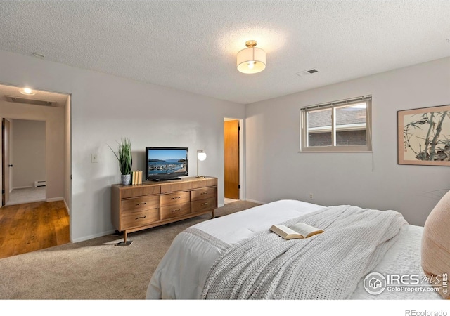 bedroom with baseboard heating, a textured ceiling, and carpet floors