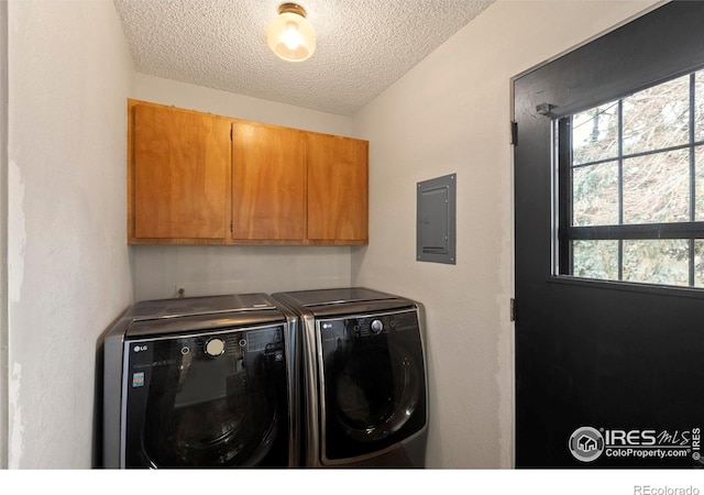 laundry room with electric panel, cabinets, washing machine and dryer, and a textured ceiling