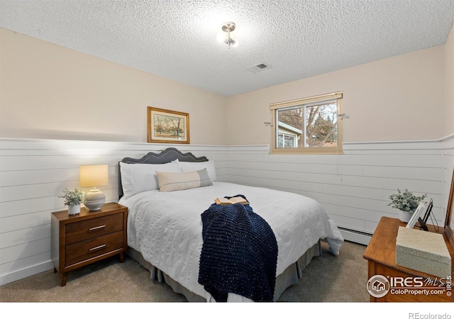 carpeted bedroom with a textured ceiling and a baseboard radiator