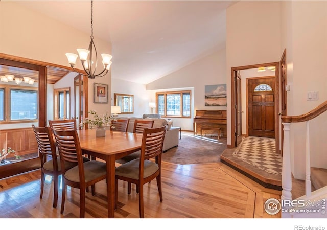 dining space with hardwood / wood-style floors, high vaulted ceiling, and a chandelier