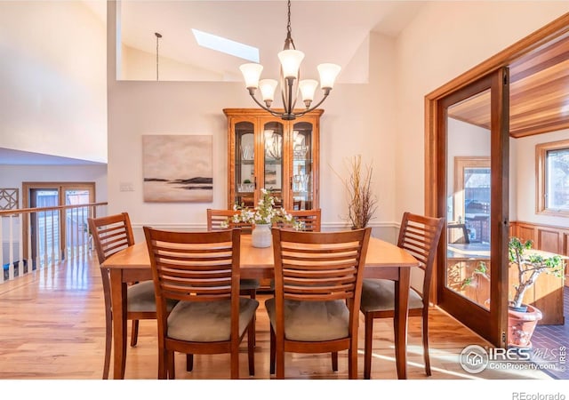 dining area featuring a chandelier, lofted ceiling with skylight, and light hardwood / wood-style flooring