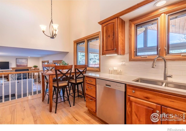 kitchen featuring stainless steel dishwasher, a chandelier, decorative light fixtures, tasteful backsplash, and sink