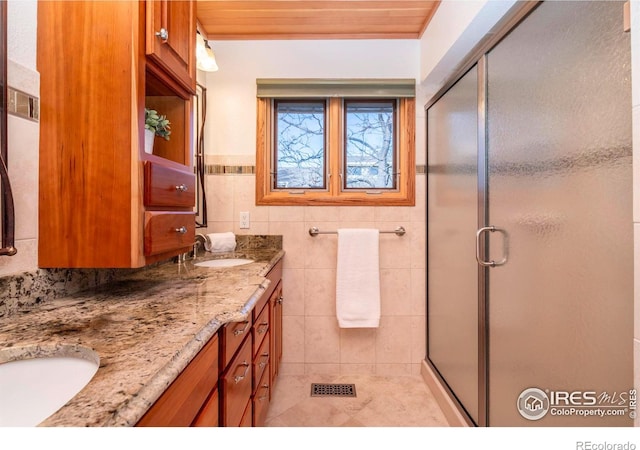 bathroom with wooden ceiling, vanity, tile patterned floors, tile walls, and a shower with shower door