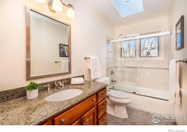 full bathroom featuring toilet, enclosed tub / shower combo, a skylight, and vanity